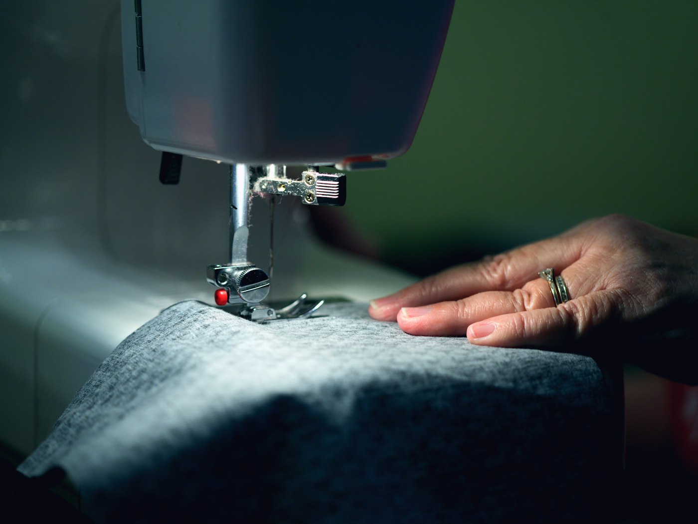 Mains guidant un tissu sous une machine à coudre en atelier